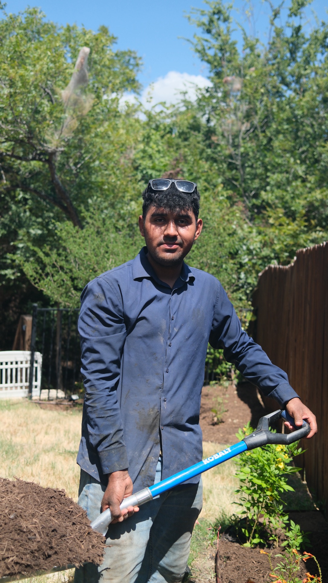 Anderson Godoy moving mulch during a Central Texas landscaping project