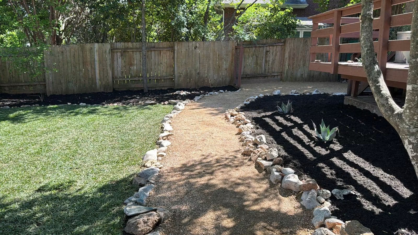 Backyard after paths, stone borders, mulch, planting, and ground-cover installation