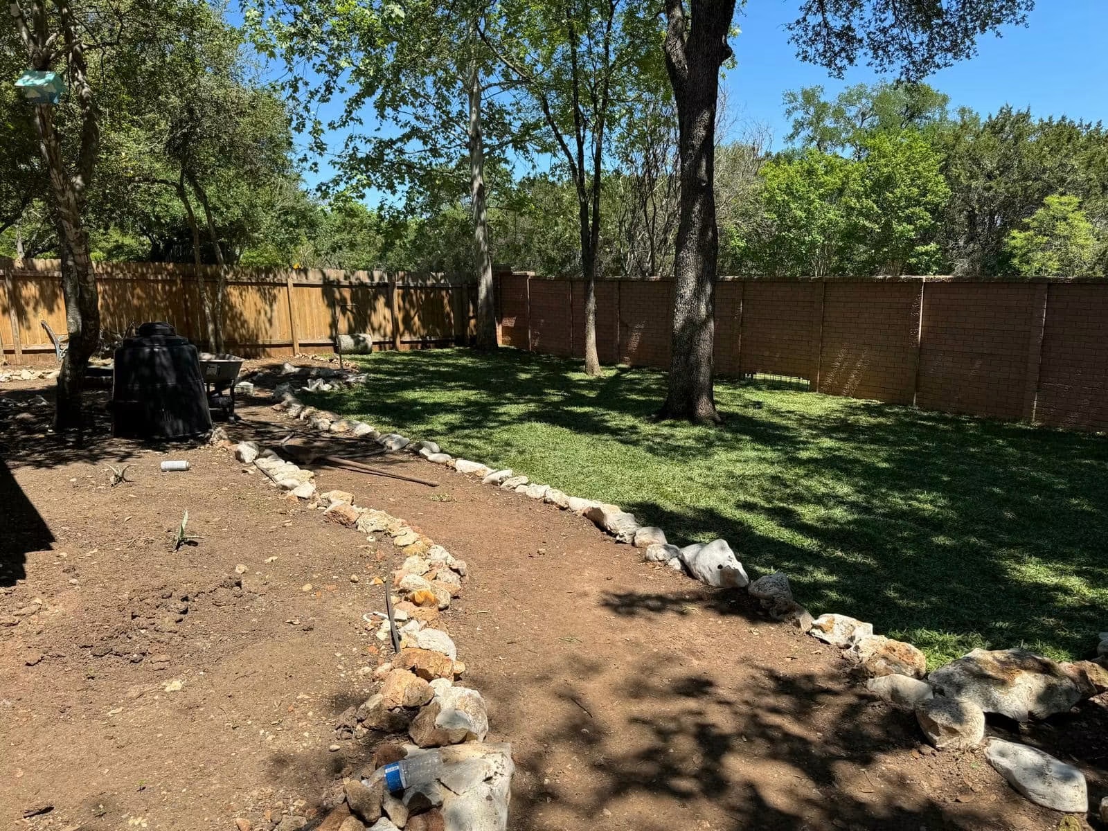 Residential backyard after ground-cover installation and stone border construction