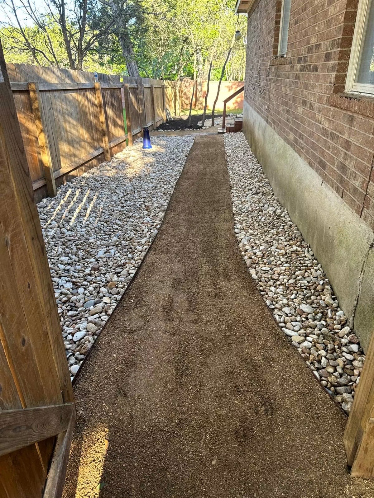 Completed side-yard river-rock path with defined landscape edging